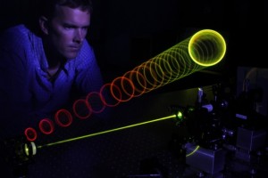 Matt Anderson looking over colored rings of laser light.