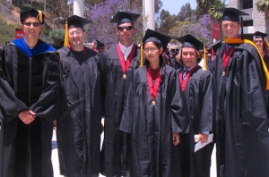 One female and six males standing in graduation outfits.