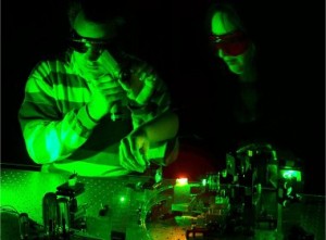 Male and Female sitting in front of laser in the optics lab.