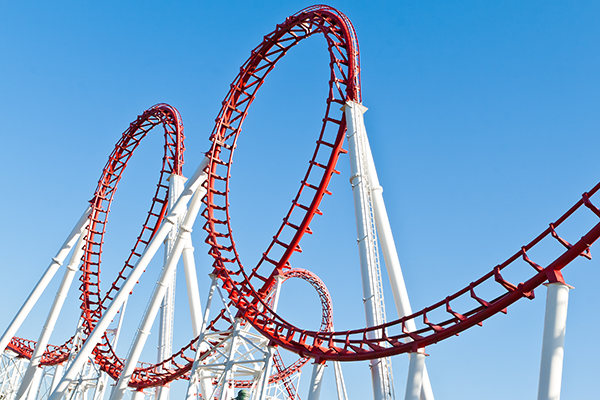 Two loops in a red and white roller coaster against a blue sky