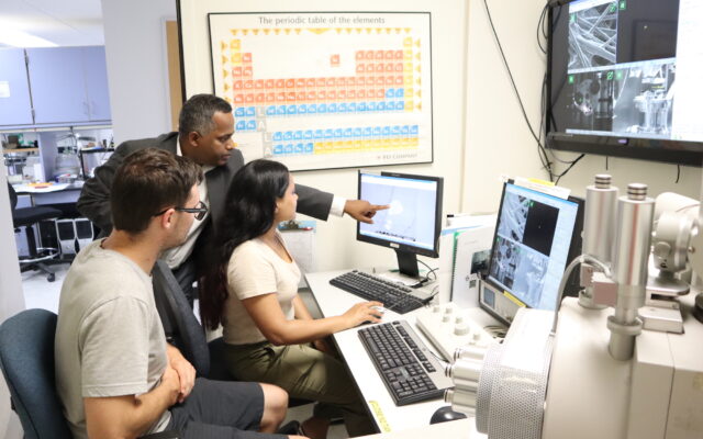 Sanjay Behura (middle) in the Electron Microscopy Facility pointing to a crystal of two-dimensional material exposed to electron beam irradiation.
