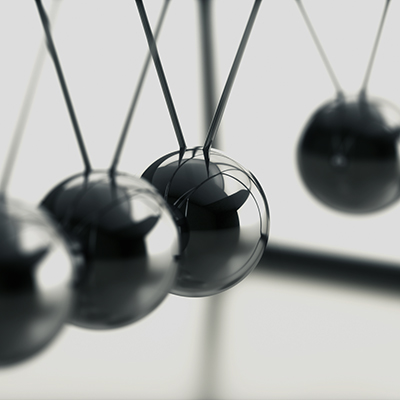 closeup of 4 stainless steel balls, each hanging from two converging lines in row.