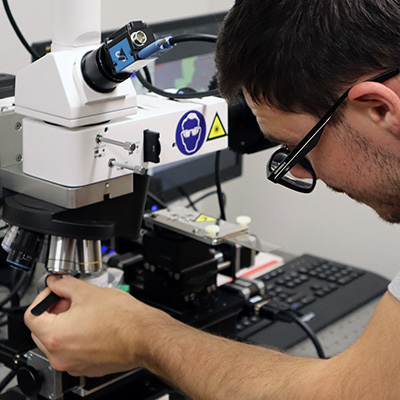 Male student using hightech microscope.